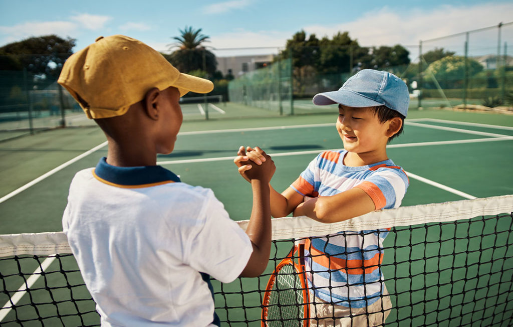two youth athletes shaking hands at tennis court