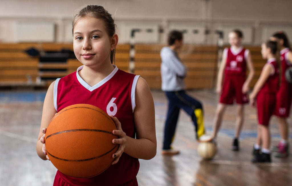 youth basketball player holding basketball with team in background