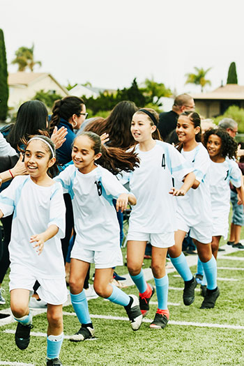 Youth girls' soccer team high-fiving fans on the sideline