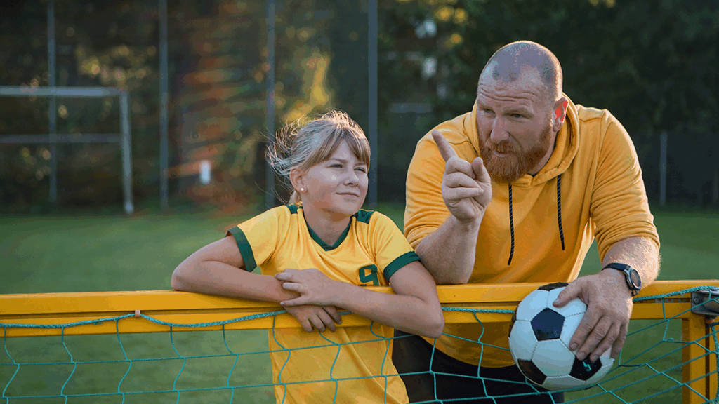 Soccer father and daughter working hard during a soccer coaching session