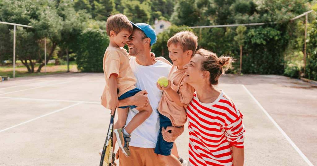 Happy family of four at the tennis court
