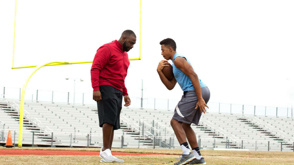 Father giving tips to an son on football techniques.