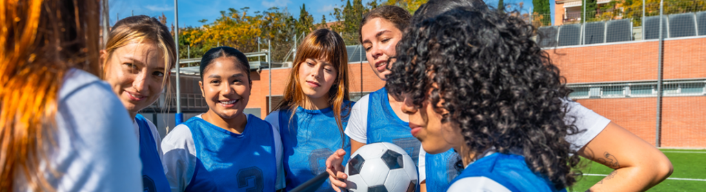 Female soccer team receiving coaching strategy on field stock